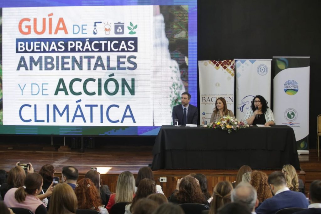 Fotografía mesa con representantes de la Defensa Pública y la Embajada Británica en Asunción, presentando la Guía de Buenas Prácticas Ambientales y de Acción Climática ante un auditorio.